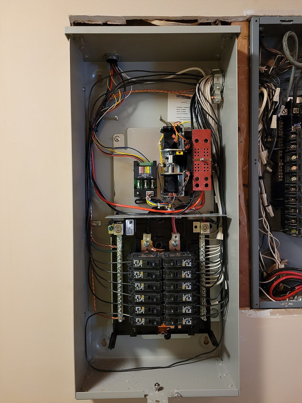 Generac automatic transfer switch with built-in breakers mounted beside an older open panel