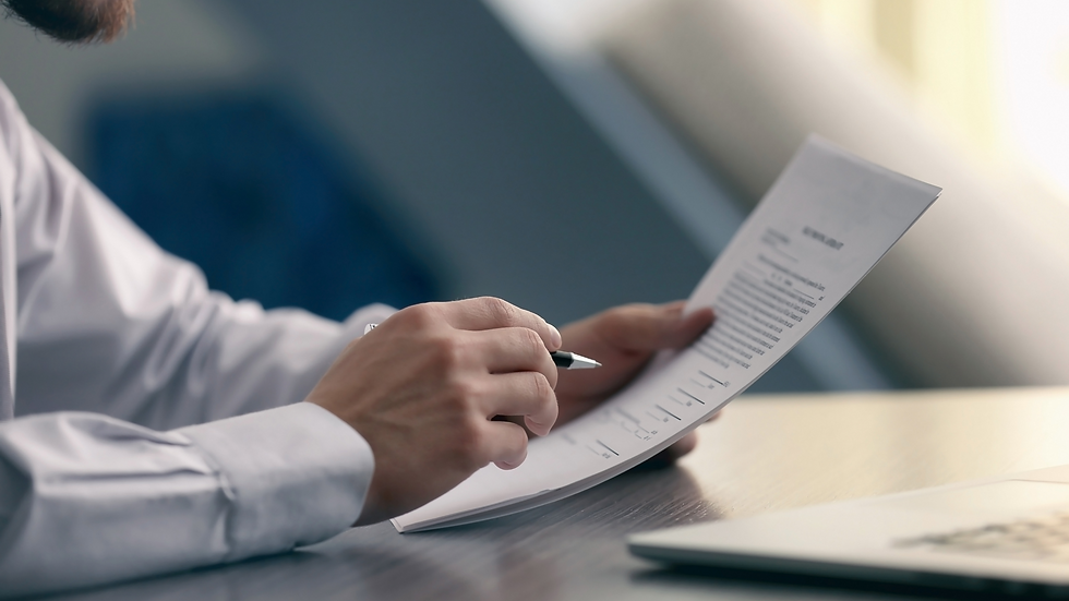 Man holding pen and documents, reading through and filling out.