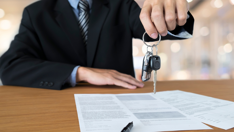 Car salesman holding car keys over some documents.