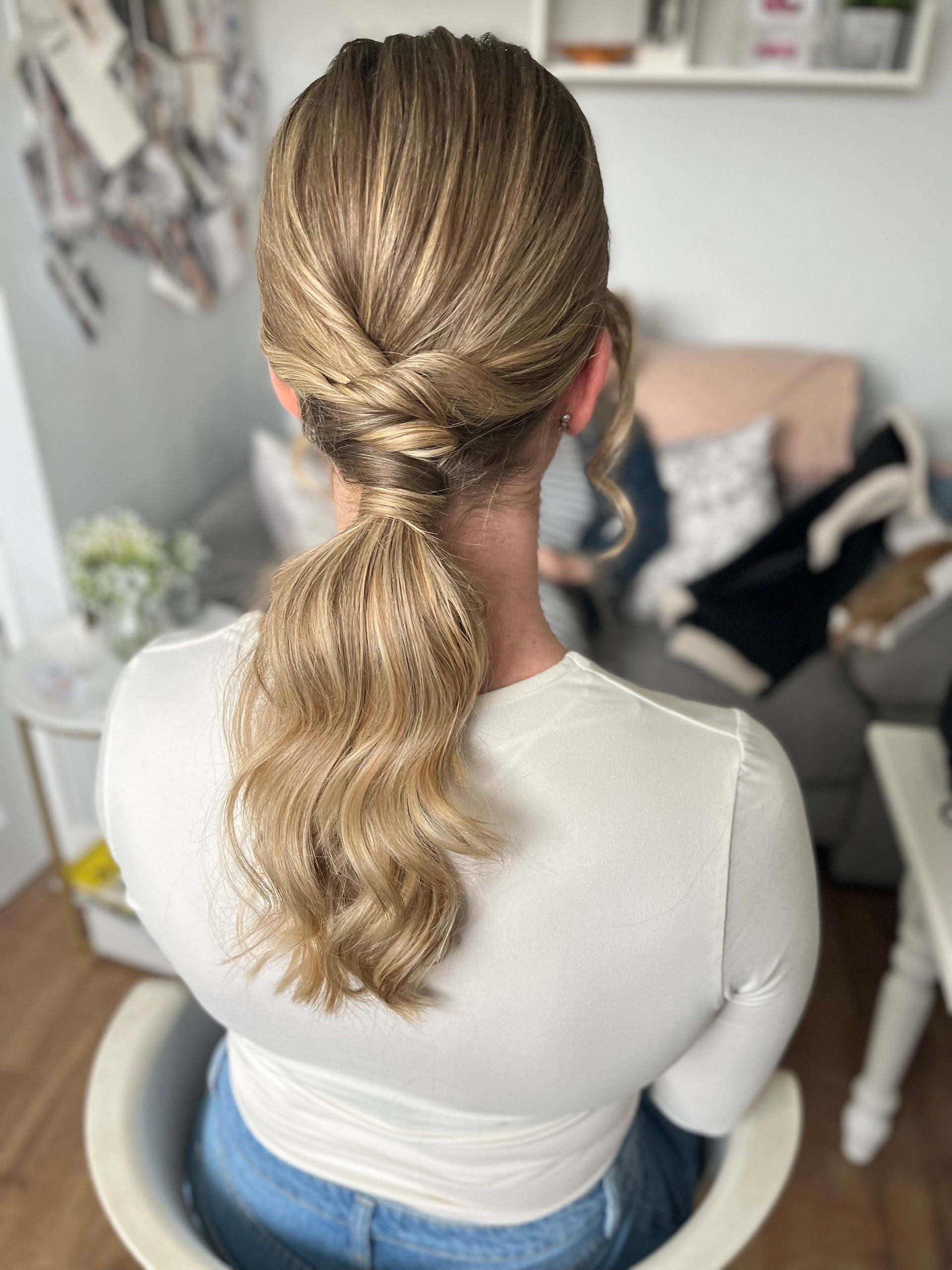 A low wavy ponytail with interesting twists and texture on a blonde haired bride to be at her trial.