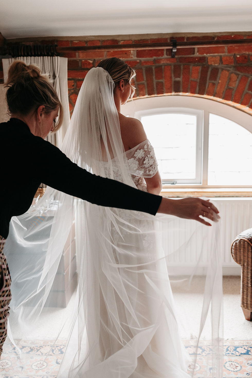 Bridal hair and makeup artist arranging veil before the bride walks down the aisle