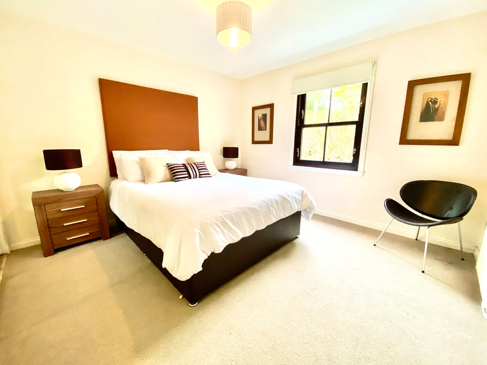 Bedroom with kingsize bed, white linen and orange headboard