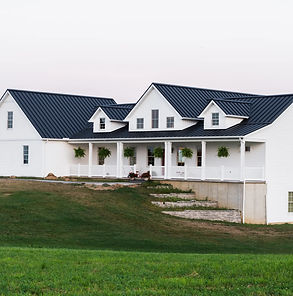 Modern, custom built farmhouse in Ashland County with white siding, black metal roof, and large front porch.