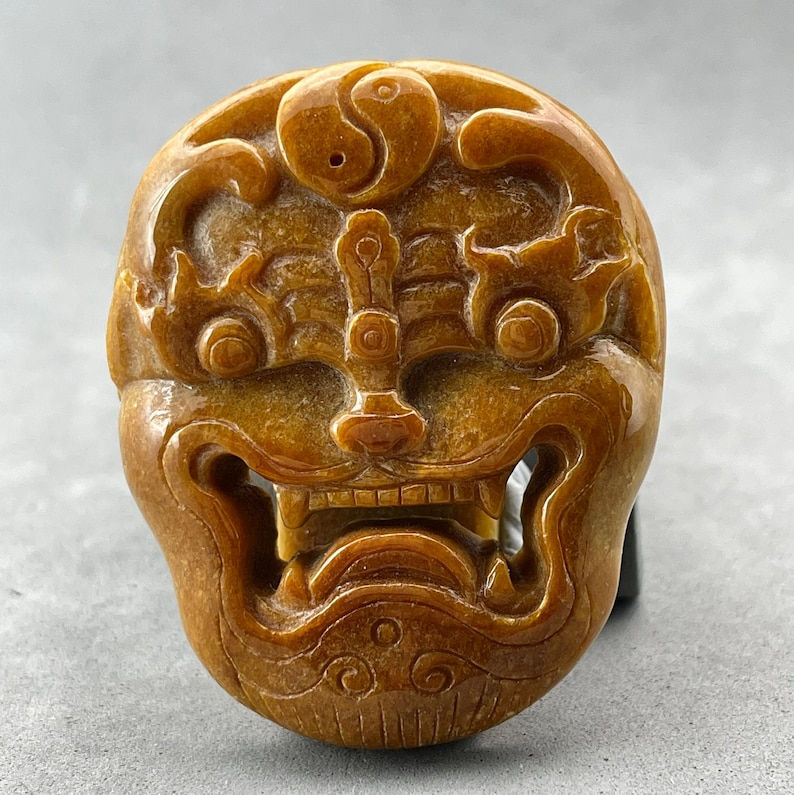 Hand carved Jadeite belt buckle of a mythical beast, or a opera mask, honey