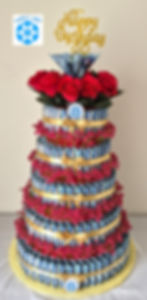 Gâteau cadeau d'anniversaire à plusieurs étages composé de billets canadiens roulés, décoré de petites fleurs roses, de ruban
