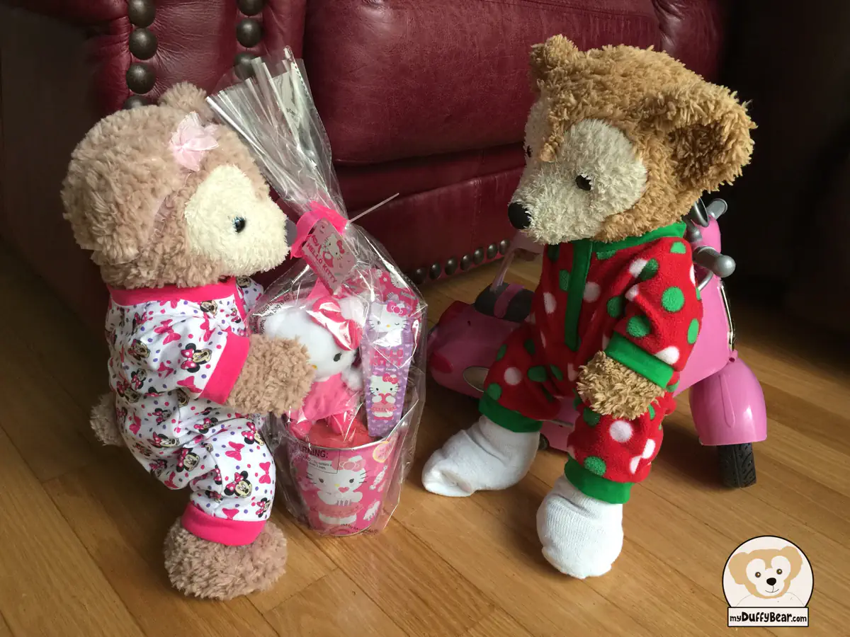 ShellieMay is holding the pink Hello Kitty gift. There is a Hello Kitty plush doll and some candy inside a pink metal bucket with Hello Kitty decorations wrapped in cellophane