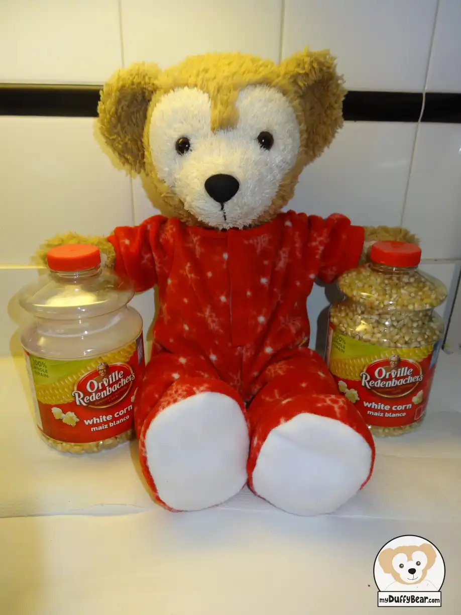 Duffy is holding a jar of  Orville Redenbacher's Popcorn on either side of him