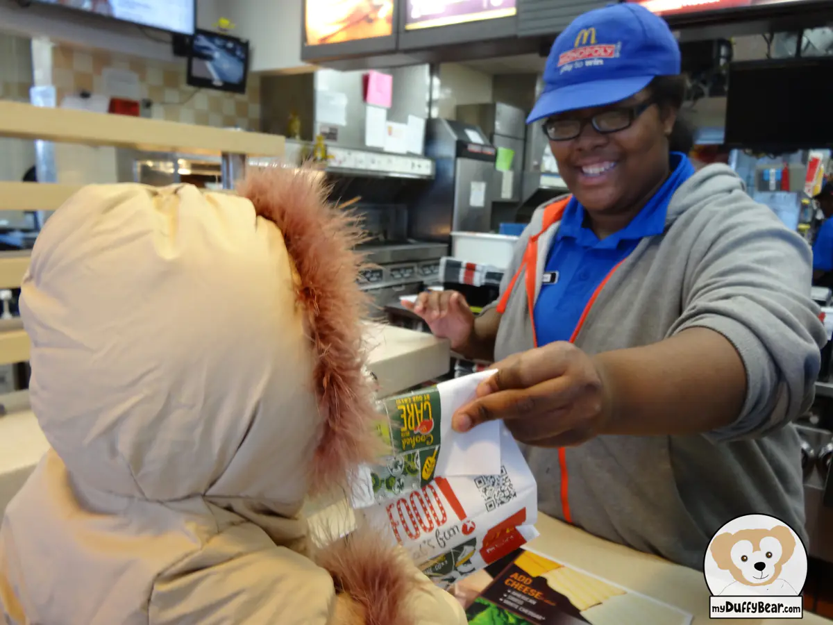 The McDonald's associate is smiling as she hands Duffy the bag with this breakfast