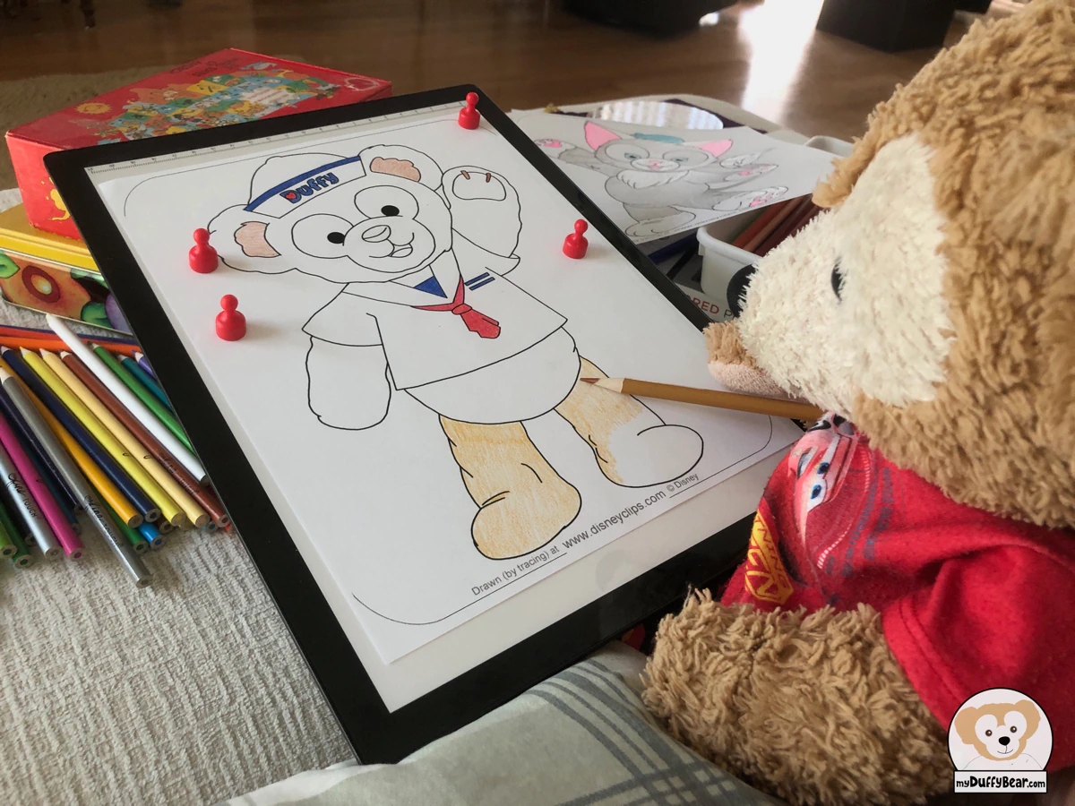 Duffy Bear is coloring a picture of Duffy the Disney Bear in his Sailor Costume