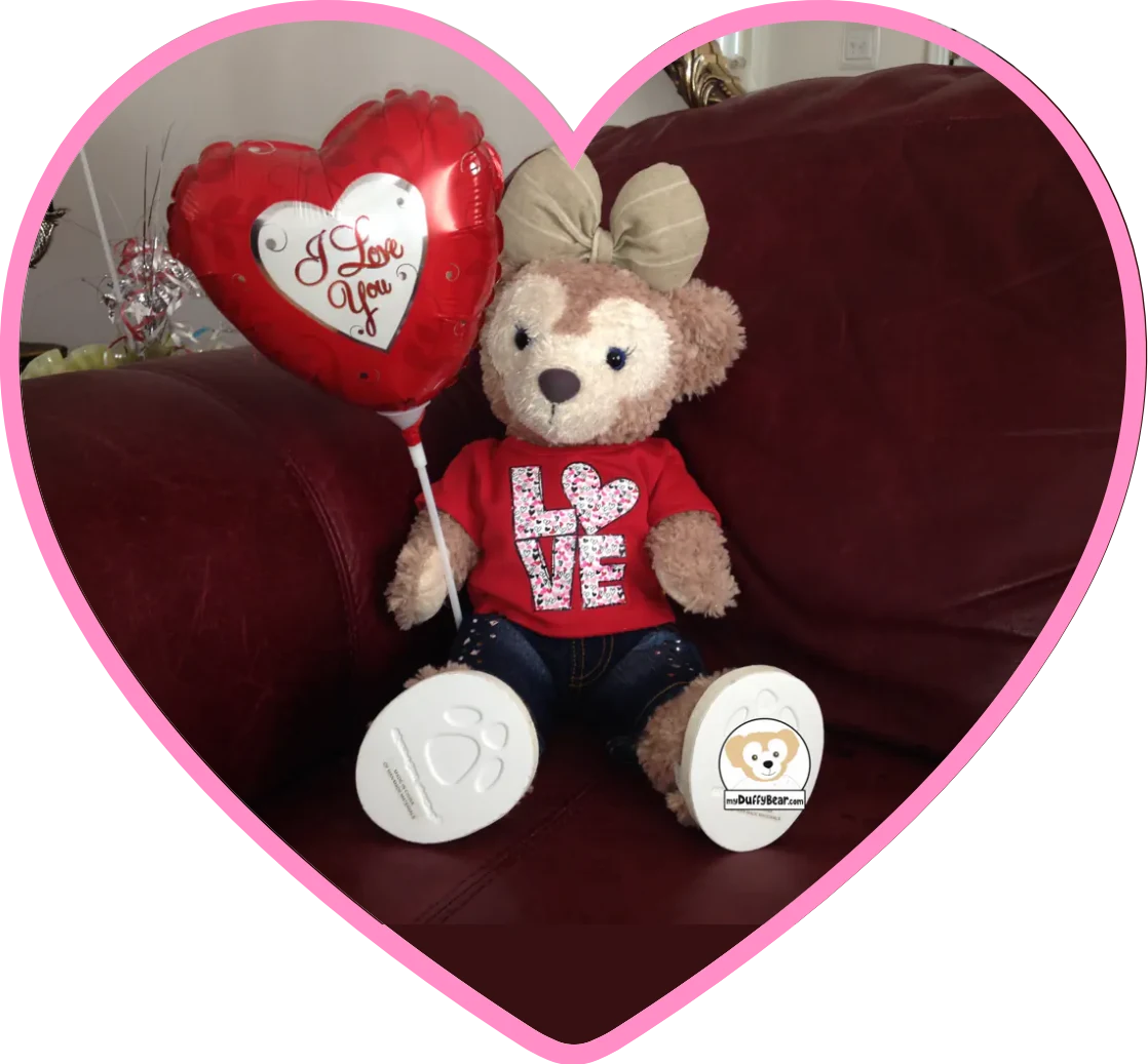 ShellieMay is holding a Valentines Day balloon and is wearing a Red Valentine's Day shirt with the letters L a heart for the letter O and VE.