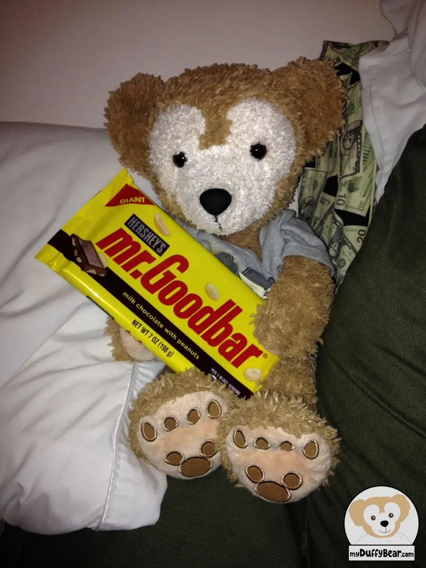 Duffy is holding a supersized mr. Goodbar candy. The candy bar is almost as big has him. 