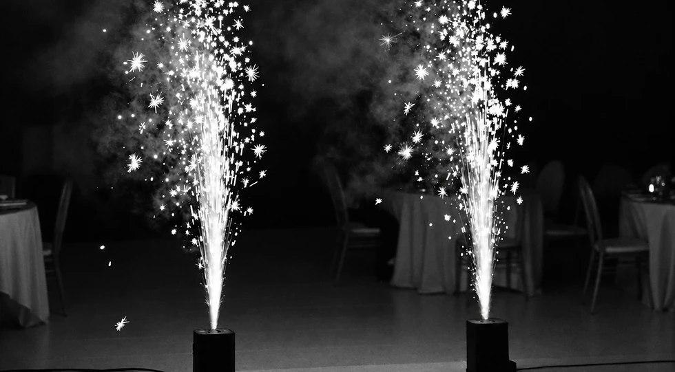 Event photography of two spark machines creating festive pyrotechnic fountains. The dramatic, high-energy display provides a celebratory atmosphere for an indoor event.