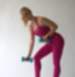 Amanda Burch in pinkem Sport Outfit hält zwei blaue Hanteln in den Händen