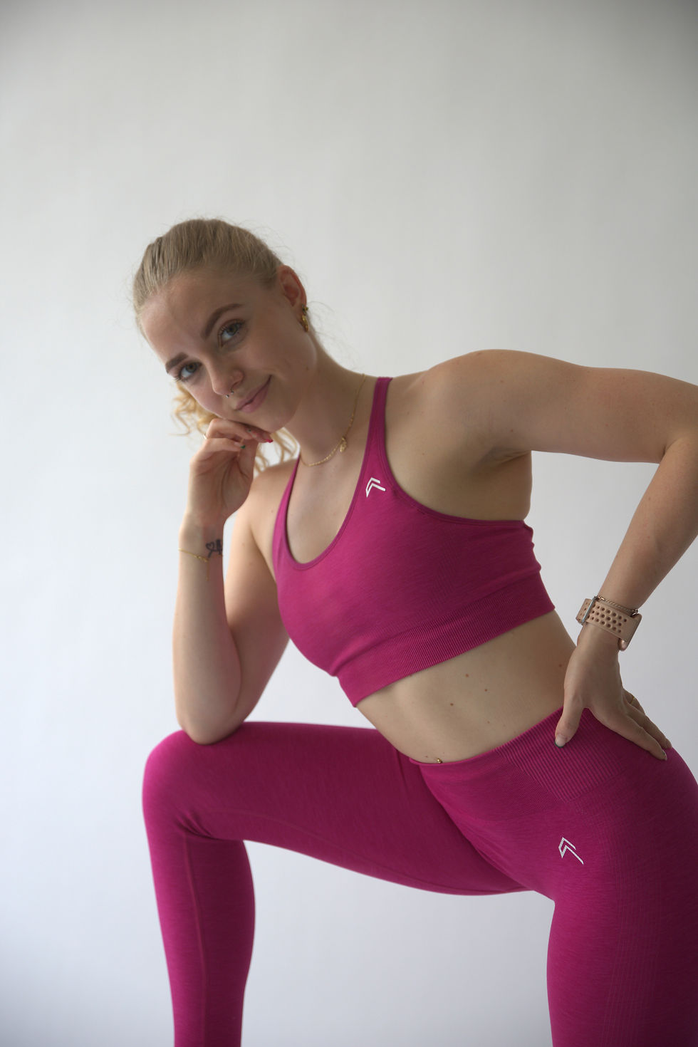 Amanda Burch in Sportoutfit stützt sich auf Knie ab und schaut in Kamera