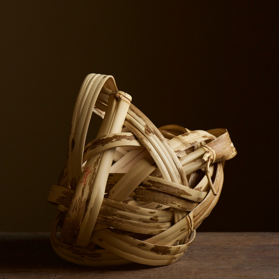 Artistic portrayal of Kosuge Kogetsu's 'Dragon's Cloud' bamboo flower basket, revealing the artist's innovative approach to traditional Japanese craft and delicate beauty.