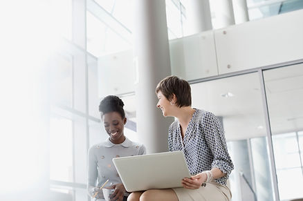 Two people sitting next to each other, at a laptop, laughing and smiling Two people sitting next to each other, at a laptop, laughing and smiling