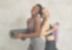 Two friends smiling holding pilates mats