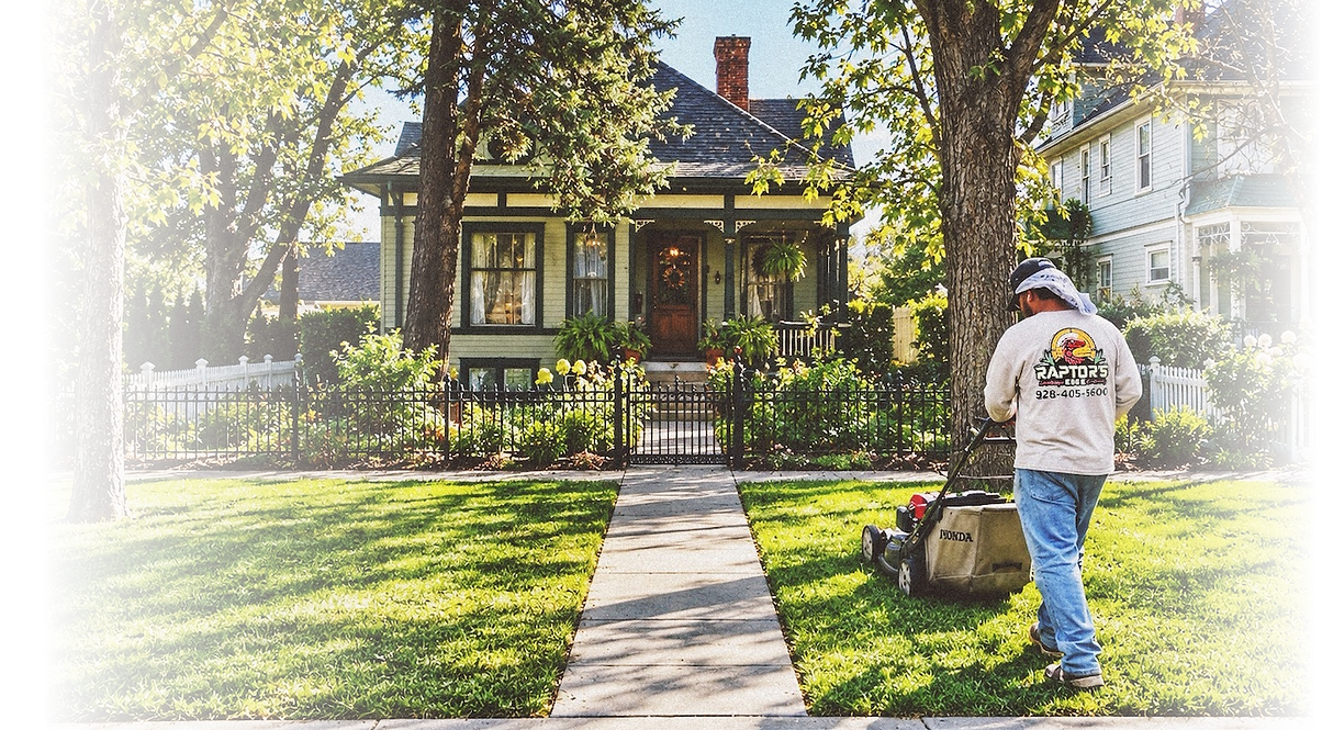 Raptors Edge crew member mowing a front lawn outside a historic-style home.