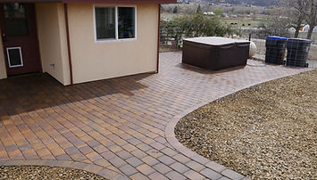 Completed Raptors Edge Landscape & Gardening paver patio project with curved edge, gravel transition, and hot tub in a Presco