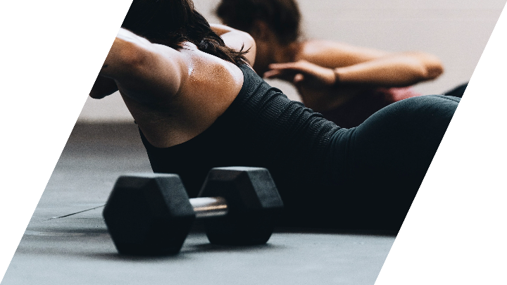 Femme qui fait exercice d'haltères sur le sol au gym sablon