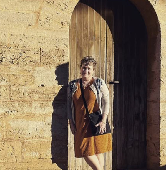 Picture of Janice Blumer DO, FAAO smiling and leaning against a wall