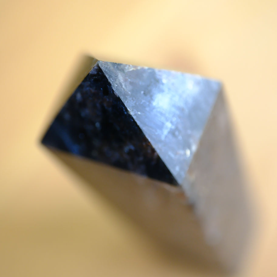 黒いピラミッド型のオブジェ、背景は黄色。ヒーリングサロンアース