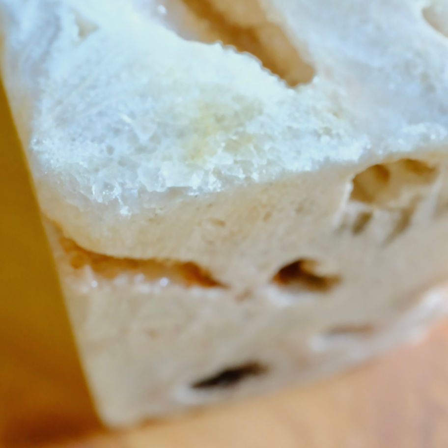 パンの断面クローズアップ写真、白い色と穴。パンの質感と詳細を強調しています。