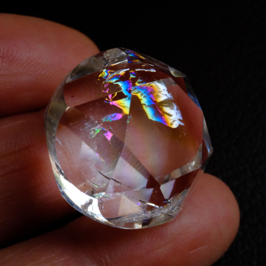 手で持つ透明な宝石、虹色の光彩、写真少ない、美しい光の反射を見せる。