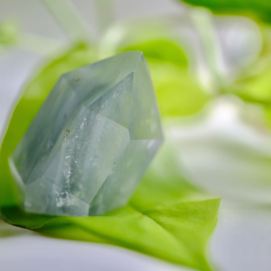 ジェダイト/トルマリン/ローズクォーツ 上の水晶原石、緑の葉の上、癒やし、ヒーリングサロンアース