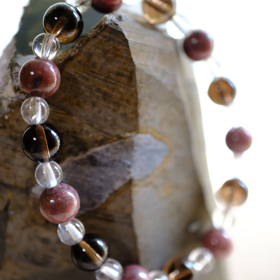 ジェダイト/トルマリン/ローズクォーツ ブレスレット、美しい色の宝石、背景に岩石、ヒーリングサロンアース