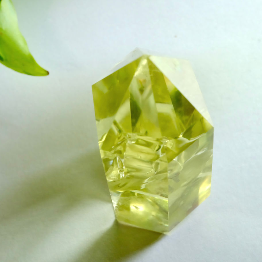 透明感のあるイエロークォーツの結晶、背景に葉。 ディープローズクォーツ/インカローズの色合い。