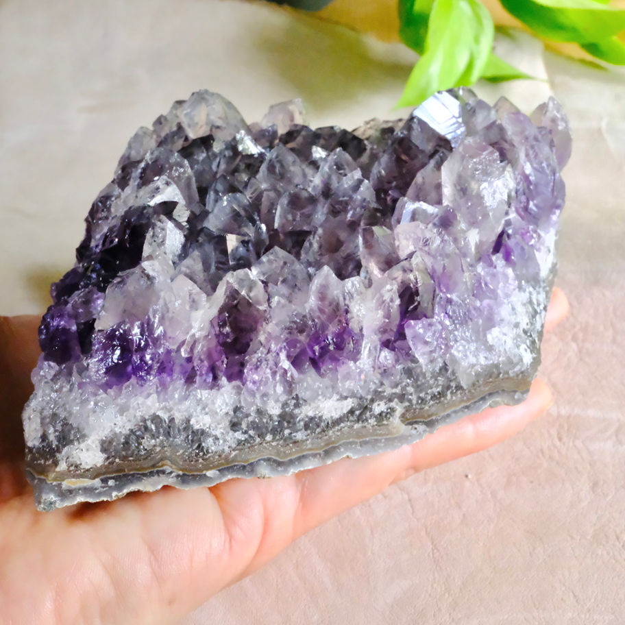 紫水晶の結晶と手。癒やしの石。紫色の美しさ。自然の中で見つける神秘的な石。