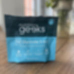 Blue and black packaging of Nutrition Geeks Magnesium Glycinate 3-in-1 on a wooden table. Text highlights benefits like reducing fatigue.