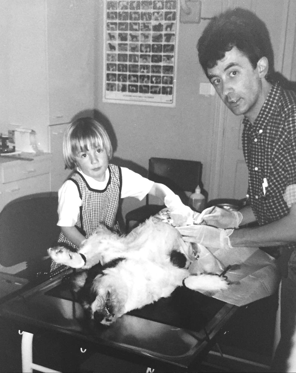 Zwart wit foto van een jonge Inne Vos die haar vader, dierenarts Dany Vos helpt bij de sterilisatie van een hond in de dierenartspraktijk.