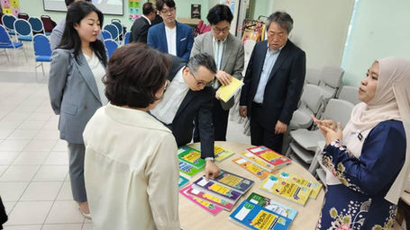 Woman in hijab discusses educational books with a group of people from South Korea