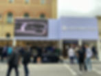 People gather outside a Leapmotor showroom. A large screen reads "Ambient Lighting: Feel the rhythm." The mood is lively and engaging.