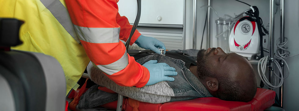A paramedic in a yellow and red uniform checks a patient's vitals with a stethoscope inside an ambulance