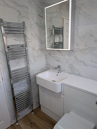 A bathroom featuring a sleek marble wall and a modern white sink, showcasing a clean and elegant design