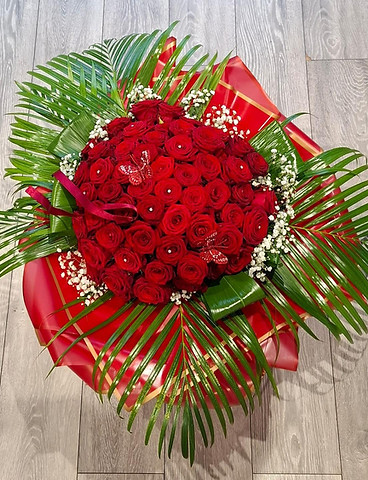 Luxurious bouquet of red roses with pearl centers, surrounded by lush green leaves