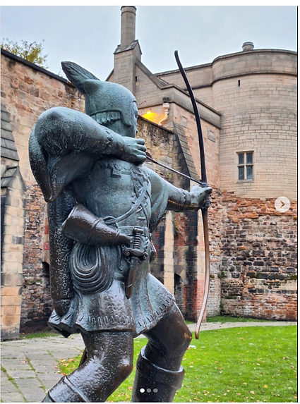 A bronze statue of an archer ready to shoot stands against a historic brick wall