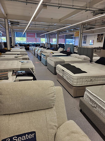A spacious room filled with numerous mattresses and pillows arranged neatly for display or sale