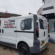 White commercial van parked on a street showing professional black and red trade business graphics.