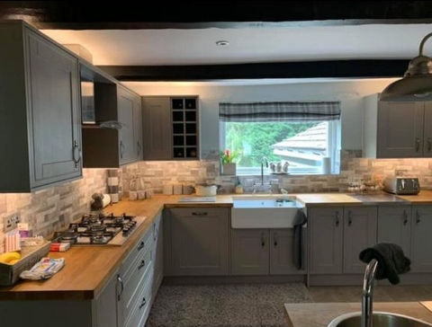 L-shaped kitchen with grey cabinets and wooden countertops