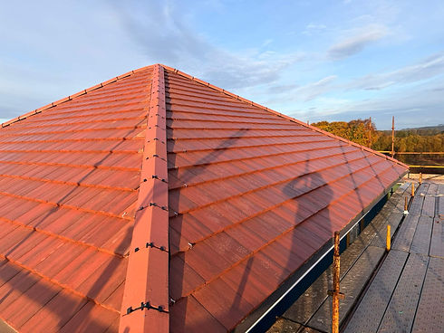 A terracotta-tiled roof glows in warm sunlight, seen from a high angle