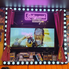 Bright pink neon sign framed beautifully above a large video display screen.