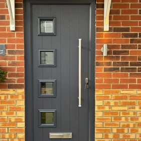 A modern gray door with four small square windows in a column