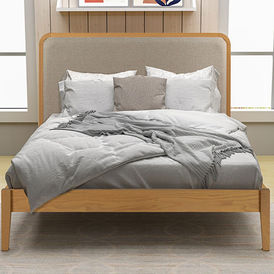 Upholstered beige headboard with a light wood frame and gray bedding