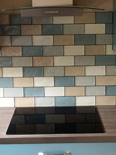 Kitchen cooking area featuring a black glass hob and multi tonal blue and grey metro splashback tiles