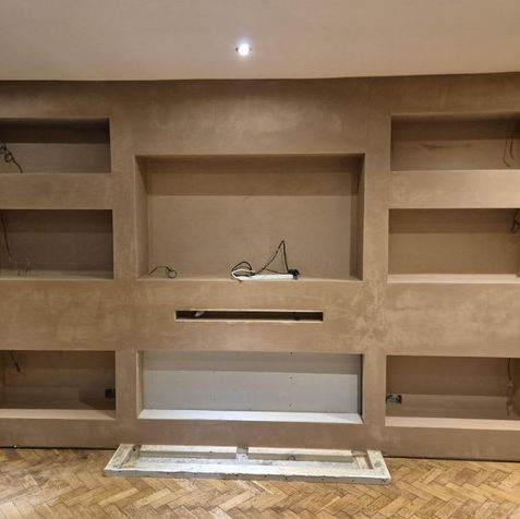 Custom built media wall with neatly plastered alcoves and recessed shelving spaces in a home