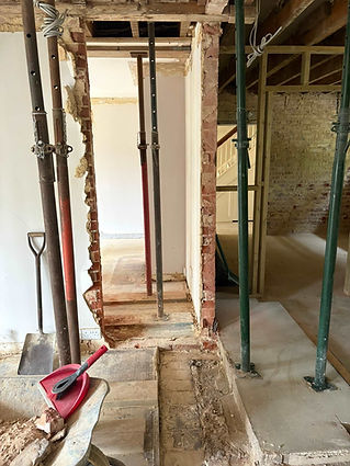 Steel acrow props supporting exposed ceiling joists and brickwork during a structural home renovation